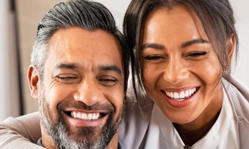 a man and woman smiling while looking at a phone